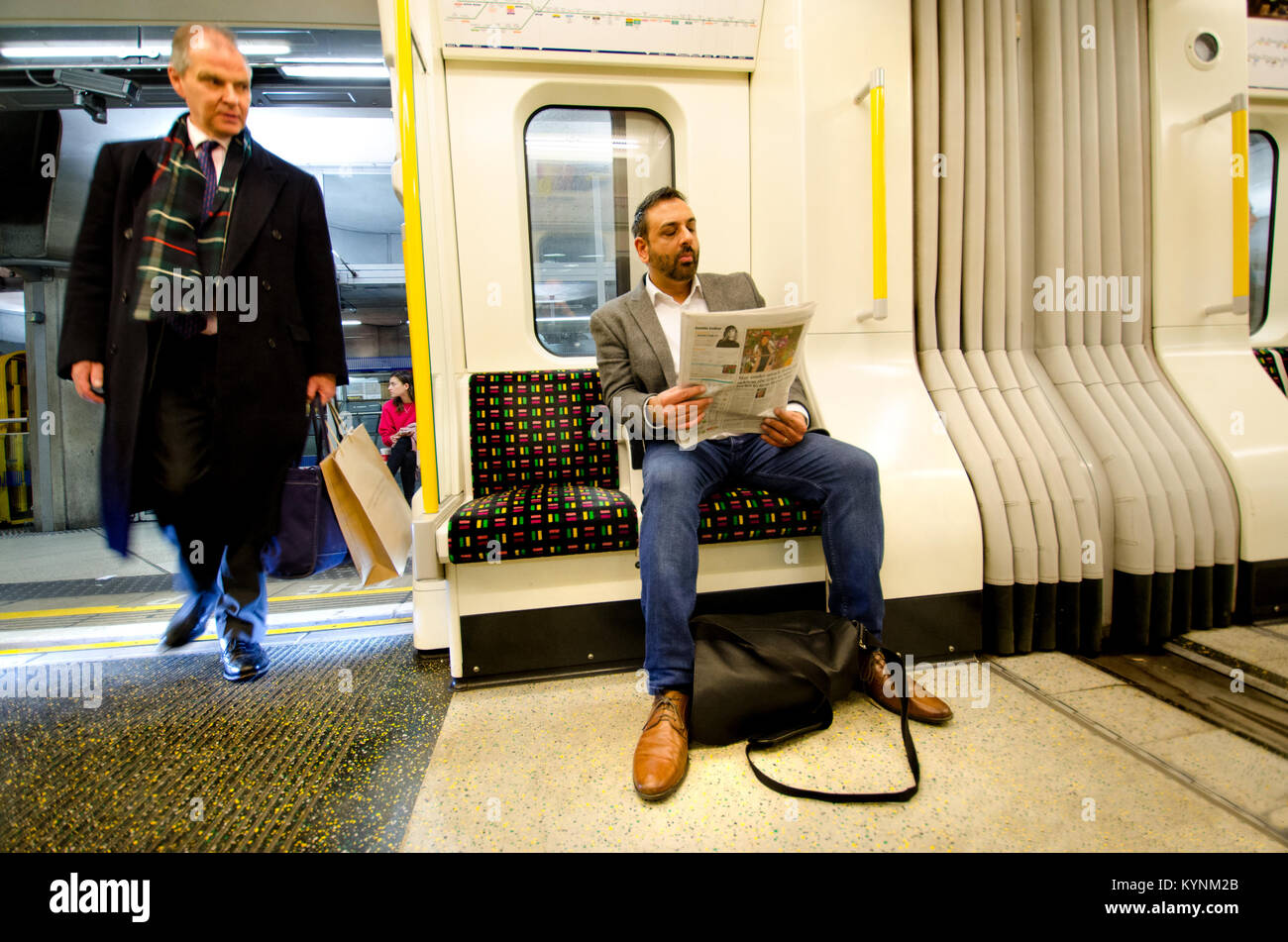 Londra, Inghilterra, Regno Unito. L'uomo leggendo un giornale su un metro di Londra treno tubo Foto Stock