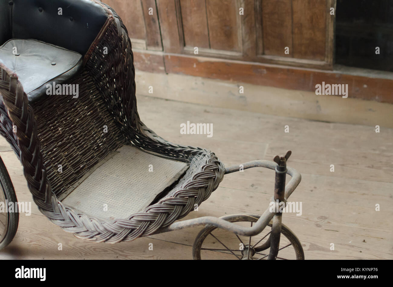 Un vintage/retrò sedia a rotelle antichi, seduto a raccogliere polvere in una vecchia casa abbandonata.... Foto Stock