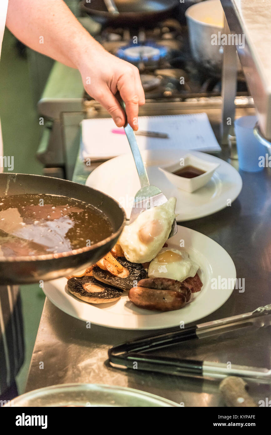 La preparazione del cibo - uno chef che prepara una colazione in un ristorante di cucina. Foto Stock