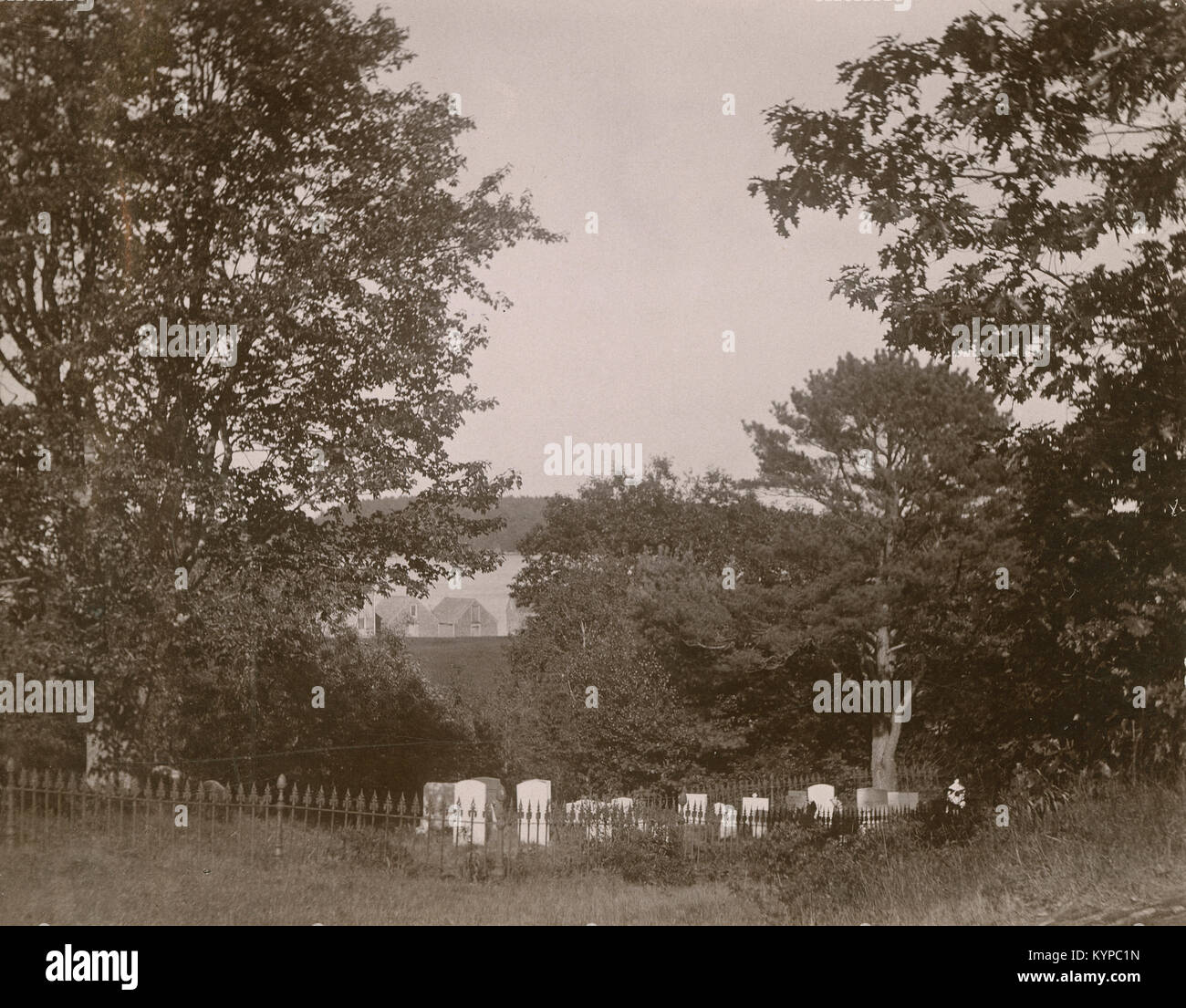 Antique circa 1905 fotografia, il piccolo cimitero con ferro battuto recinto vicino a case e fiume. La posizione è in o vicino a Riggsville (ora Robinhood), Maine in Sagadahoc County, Stati Uniti d'America. Foto Stock