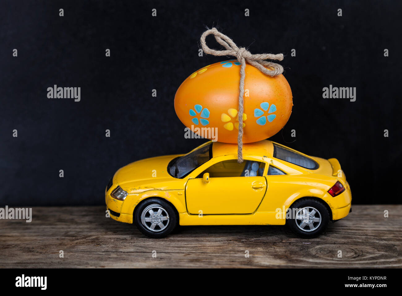 Giallo auto giocattolo con uovo di pasqua. La pasqua ancora in vita. Foto Stock