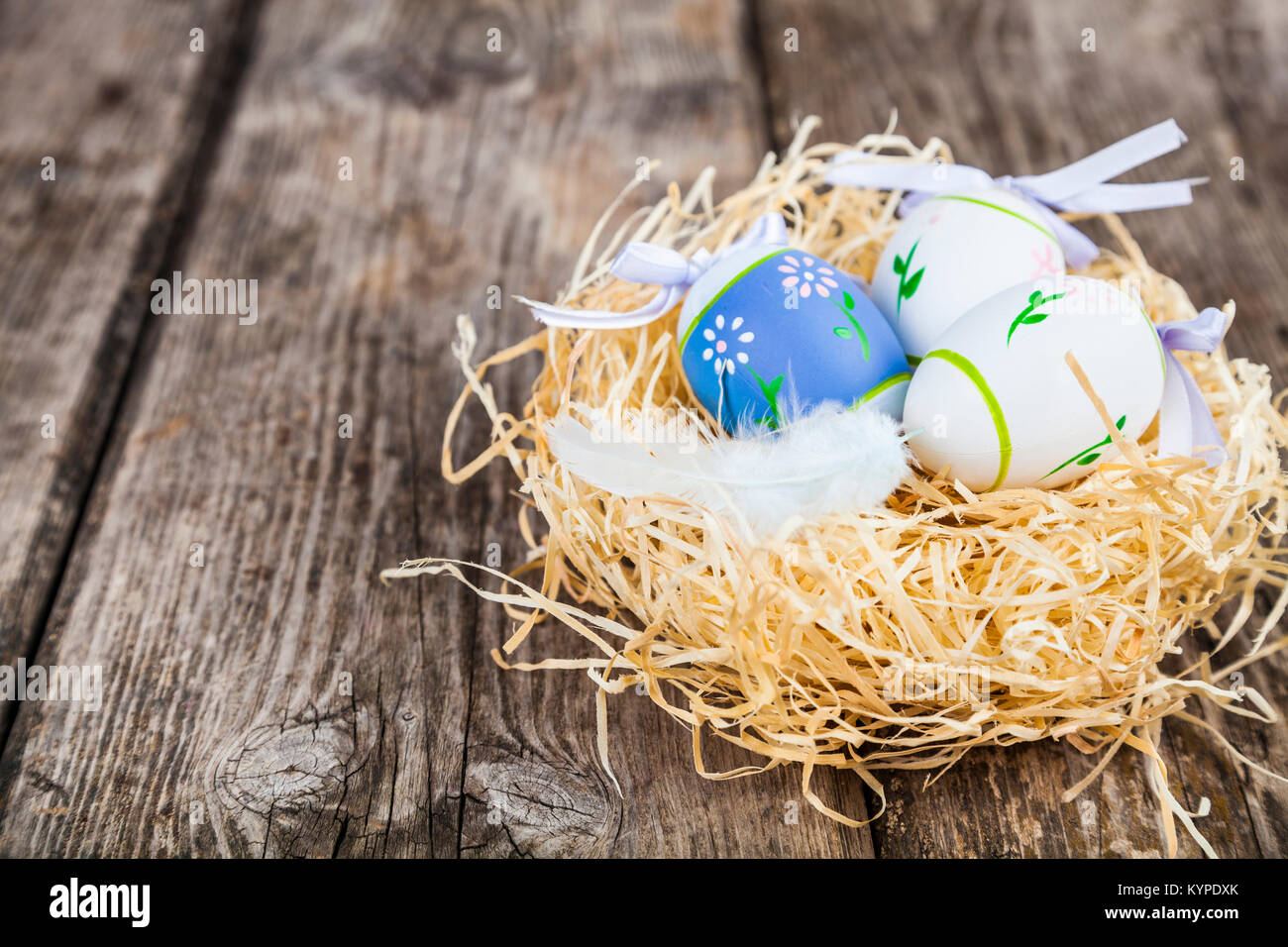 Uova di Pasqua nel nido in legno di colore dello sfondo. La pasqua ancora in vita con nido, le piume e le uova. Foto Stock