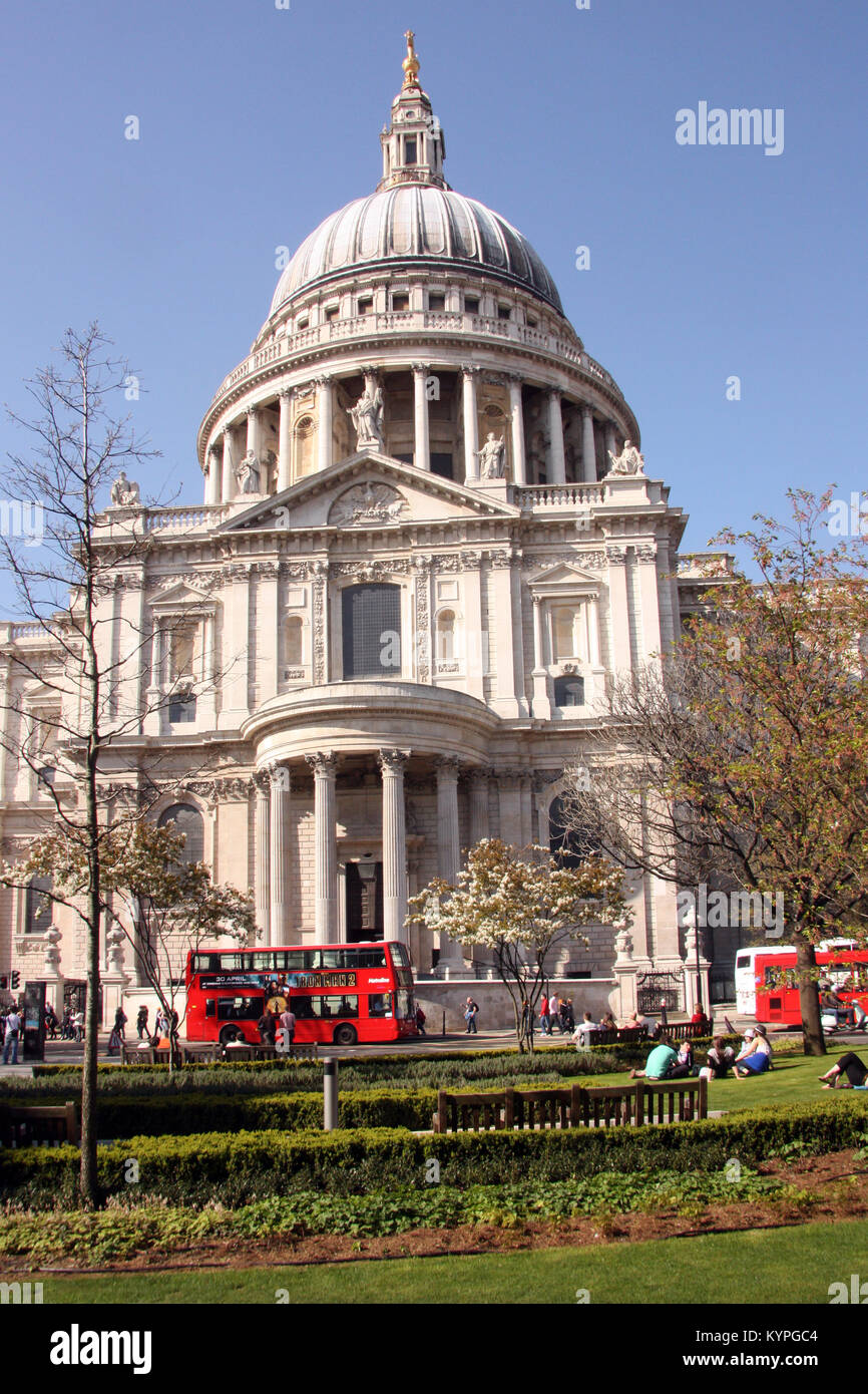 Vista della cattedrale di St Paul, Londra Inghilterra Regno Unito contro il cielo blu con red bus londinese passando davanti e gente seduta sul prato Foto Stock