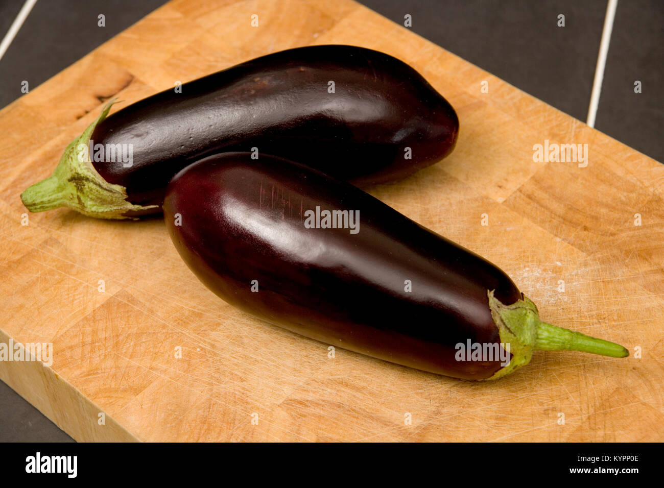 Due melanzane viola melanzane su un tagliere di legno Foto Stock