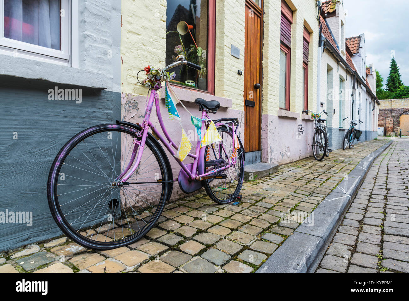 Tre biciclette parcheggiate davanti a una casa su una strada della città medievale di Bruges, Belgio Foto Stock