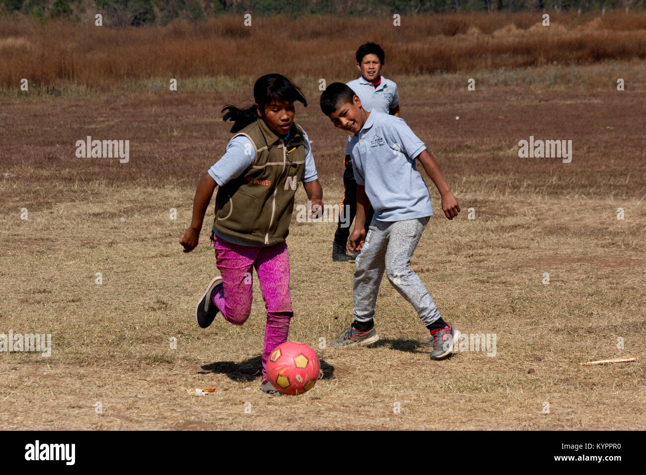 Ragazzi che giocano a calcio in un campo in Messico Foto Stock