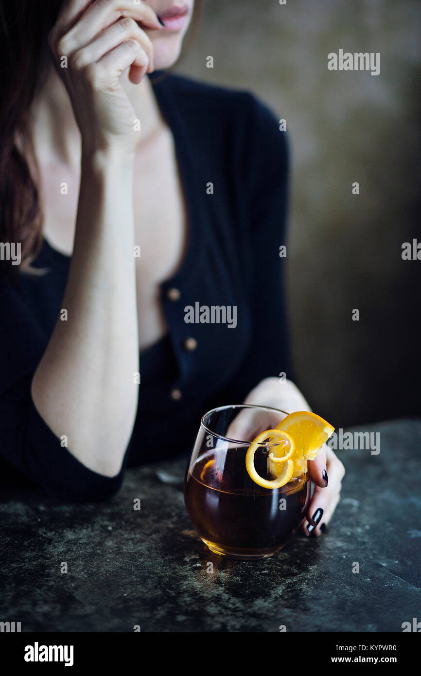 Giovane donna seduti al bar a bere una bevanda alcolica Foto Stock