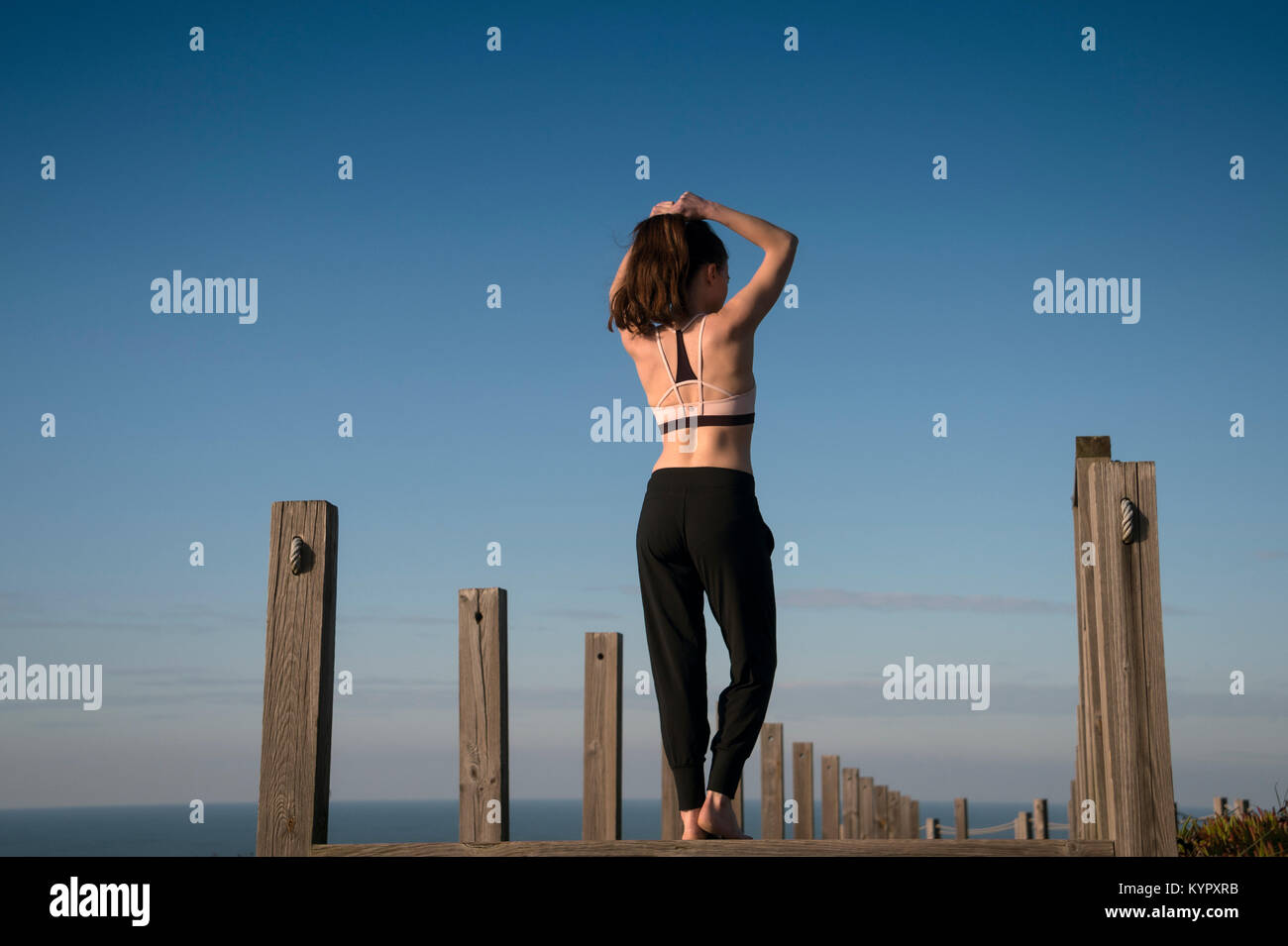 Legatura donna i capelli in una coda di cavallo prima di un allenamento fitness fuori dal mare. Foto Stock