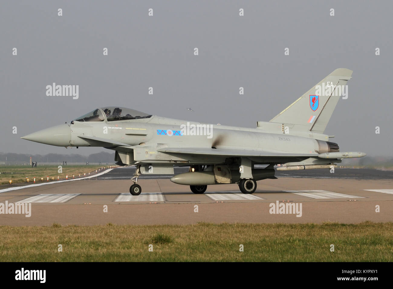 RAF Typhoon rullaggio fuori pista Coningsby dopo lo sbarco come altro emerge dalla nebbia dietro. Foto Stock