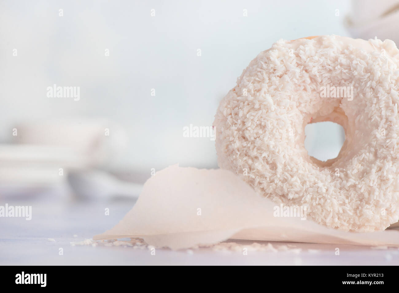 Close-up di un bianco ciambella con topping di cocco su uno sfondo luminoso. Elevato La chiave fotografia di cibo. Foto Stock