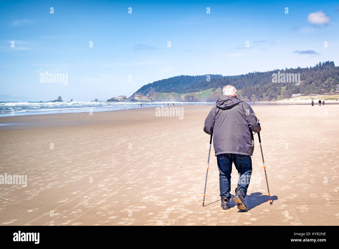 Il vecchio uomo esercizio di arrivare a piedi con pali trekking sulla spiaggia. Copia dello spazio. Foto Stock