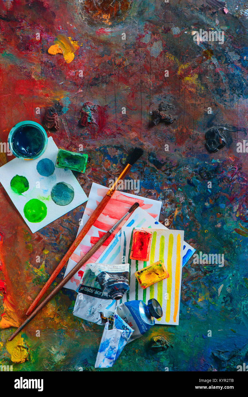 Olio colorato e acquerello tavolozza con spazzole, pitture e schizzi. Artista strumenti su uno sfondo scuro in occupazione creativa del concetto. Piatto con i laici Foto Stock