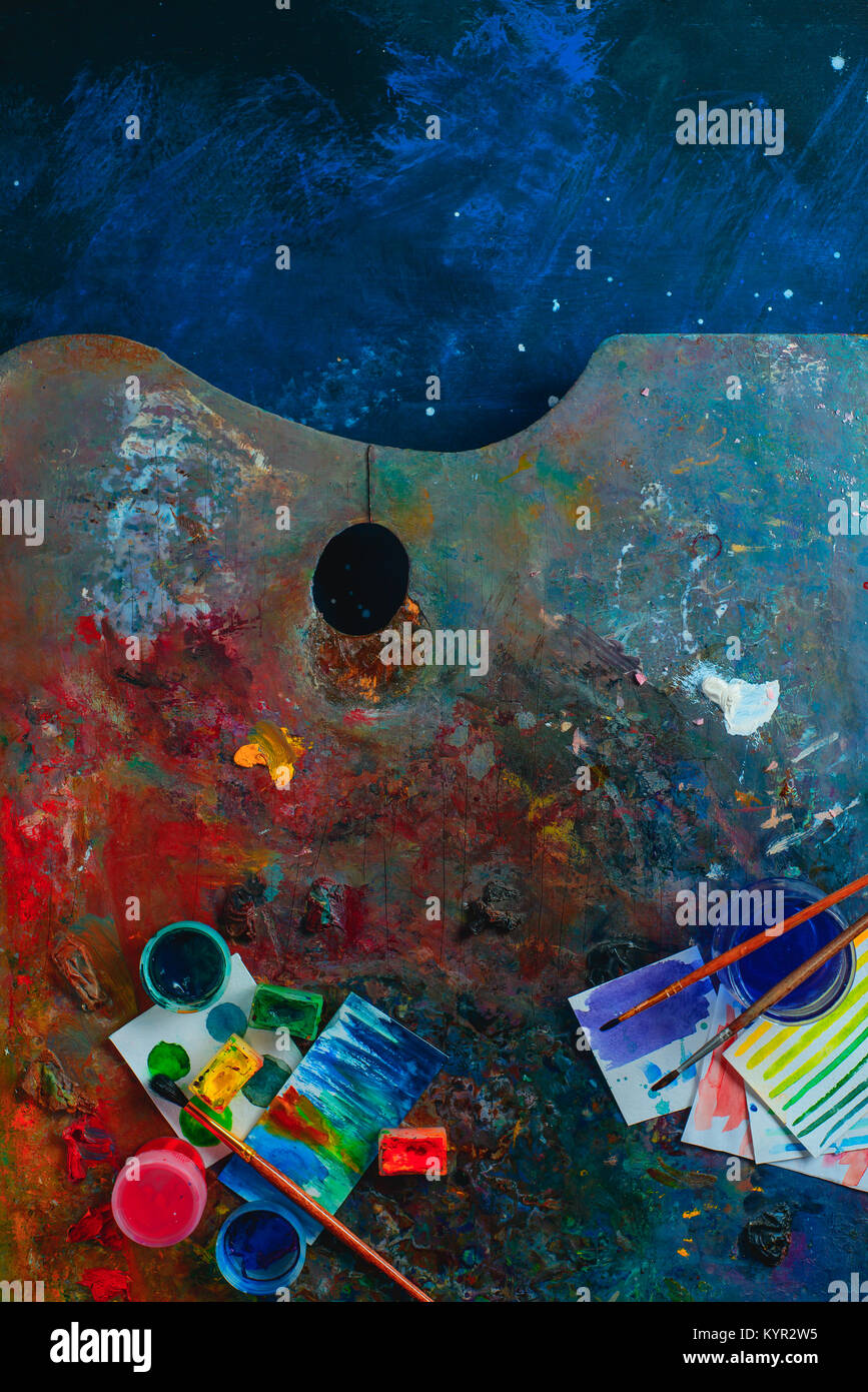 Olio colorato e acquerello tavolozza con spazzole, pitture e schizzi. Artista strumenti su uno sfondo scuro in occupazione creativa del concetto. Piatto con i laici Foto Stock