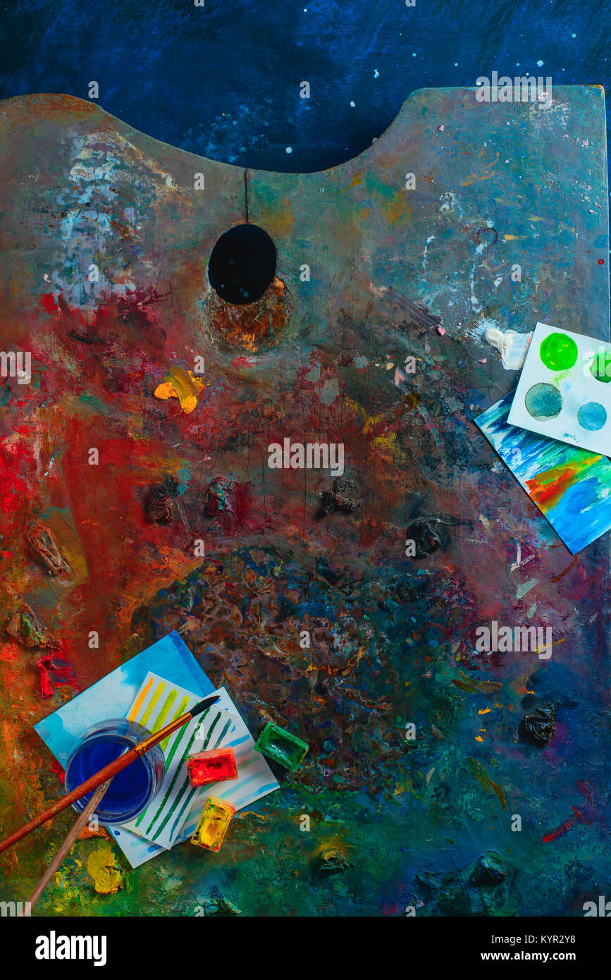 Olio colorato e acquerello tavolozza con spazzole, pitture e schizzi. Artista strumenti su uno sfondo scuro in occupazione creativa del concetto. Piatto con i laici Foto Stock