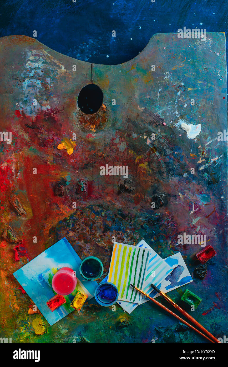 Olio colorato e acquerello tavolozza con spazzole, pitture e schizzi. Artista strumenti su uno sfondo scuro in occupazione creativa del concetto. Piatto con i laici Foto Stock