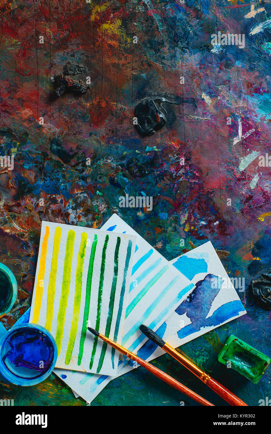 Olio colorato e acquerello tavolozza con spazzole, pitture e schizzi. Artista strumenti su uno sfondo scuro in occupazione creativa del concetto. Piatto con i laici Foto Stock