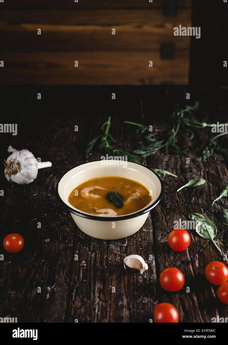Zuppa di gamberetti nella ciotola con i pomodori e le erbe sul tavolo di legno Foto Stock