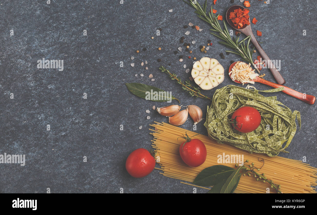 Selezione di spezie, pasta e verdi. Ingredienti per la cottura della pasta. Sfondo scuro, vista dall'alto, copia dello spazio. Foto Stock