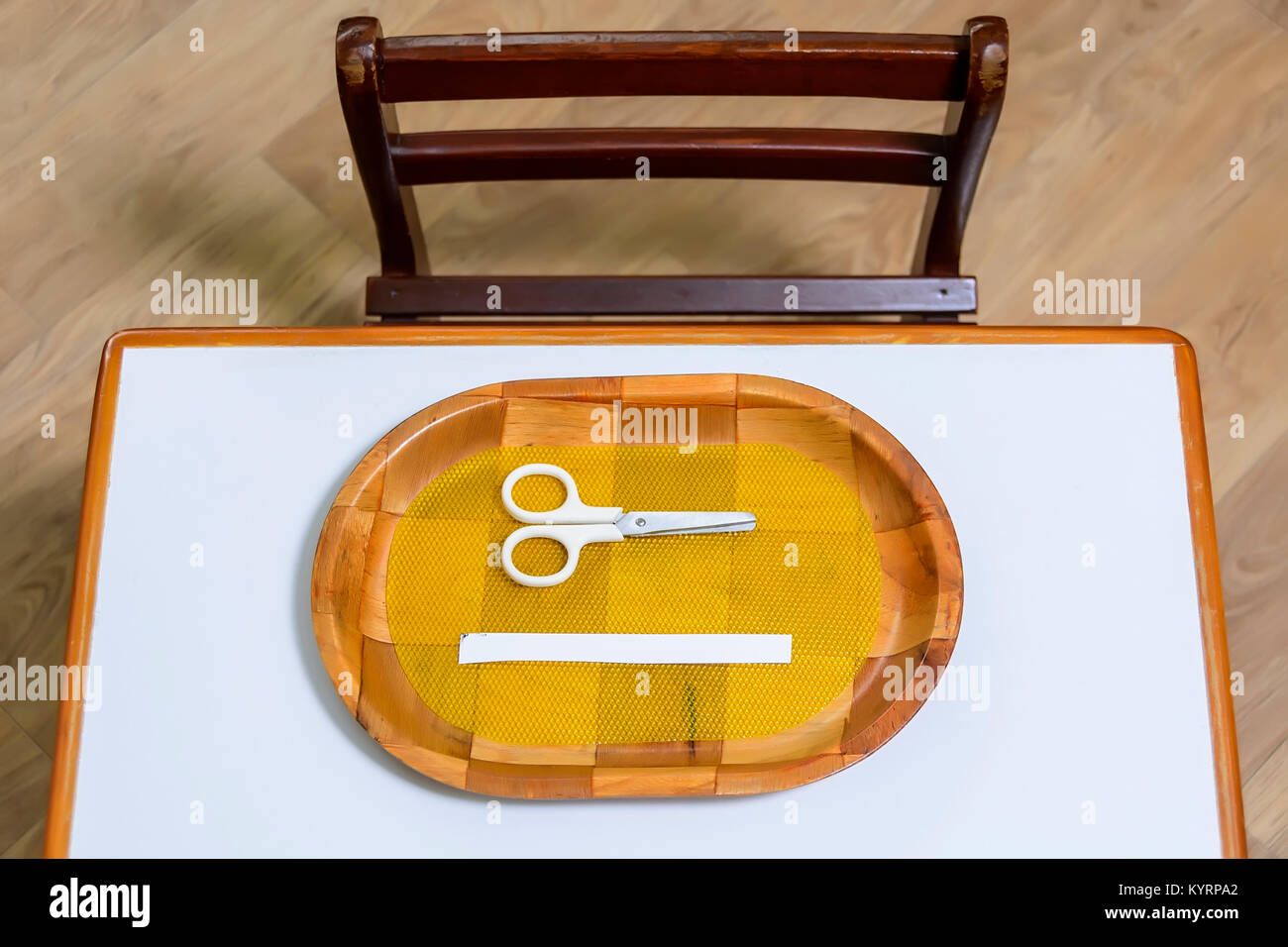 I bimbi a scuola per scrivania e sedia con forbici e un pezzo di carta bianca su un vassoio Foto Stock