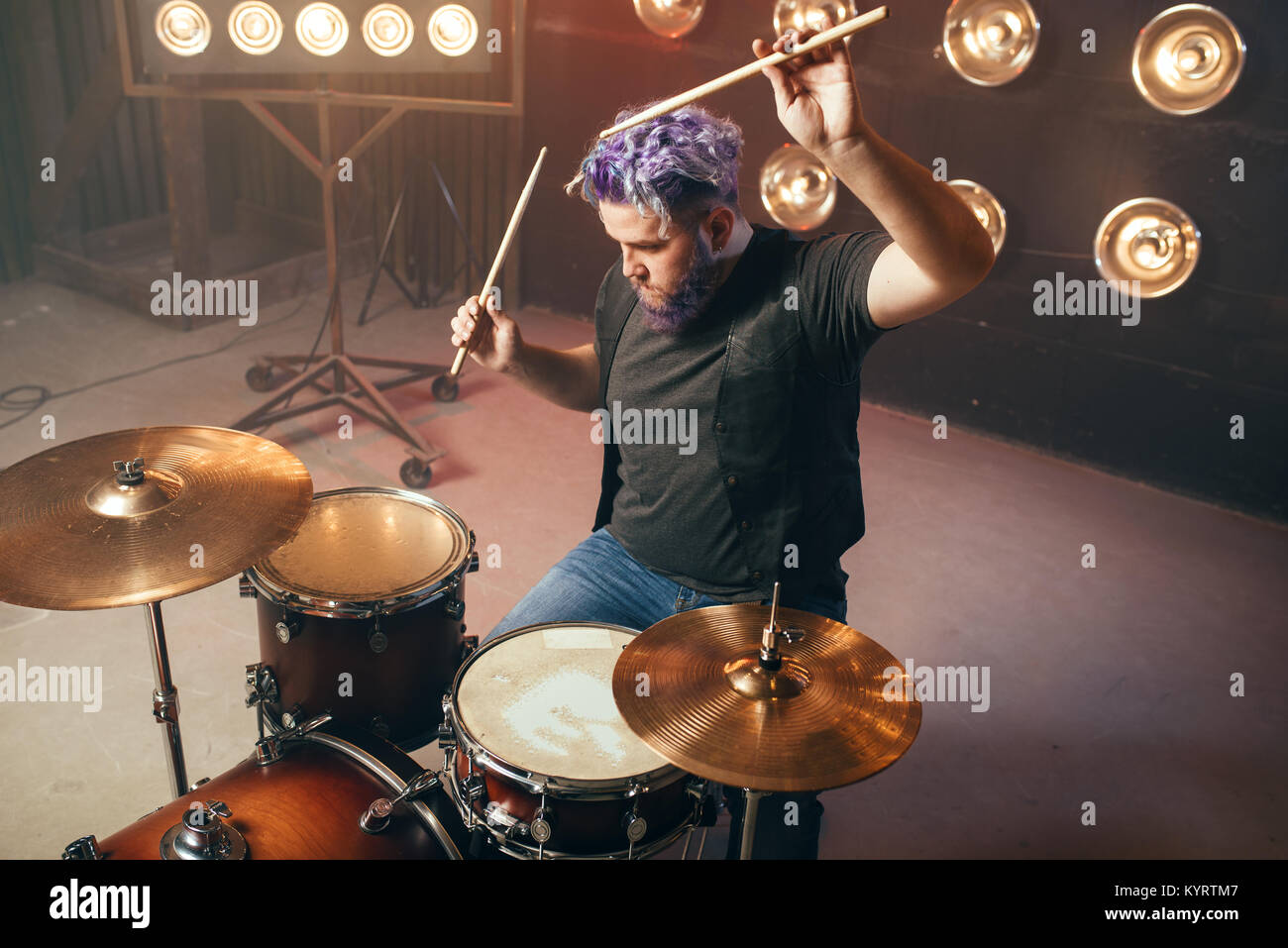 Batterista Barbuto con i capelli colorati sul palco con luci, in stile vintage. Performer musicali, musica live performing Foto Stock