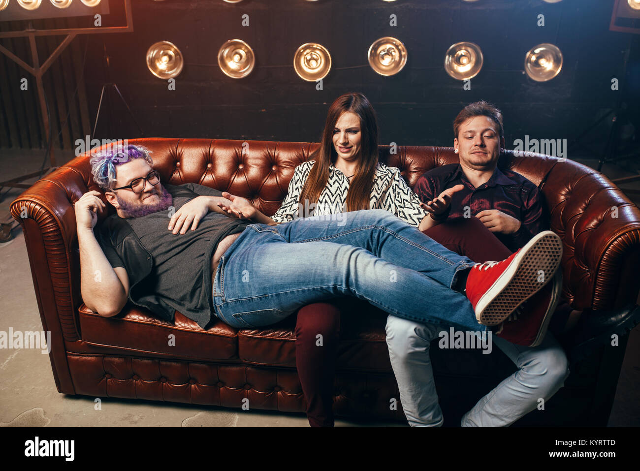 Felice amicizia, threesome ha-ha sul divano, partito in music studio. Gli  amici si siede sul divano e ridere Foto stock - Alamy