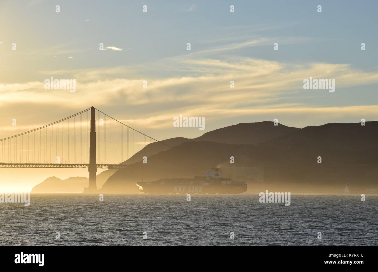 Contenitore nave NYK costellazione lascia San Francisco Bay sotto il Golden Gate Bridge verso il tramonto. Foto Stock