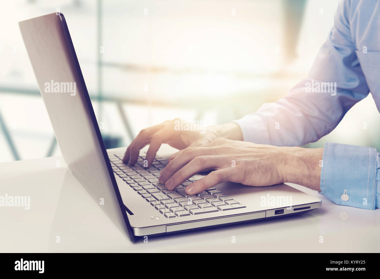 Imprenditore moderno lavorando sul computer portatile in bright sole ufficio Foto Stock