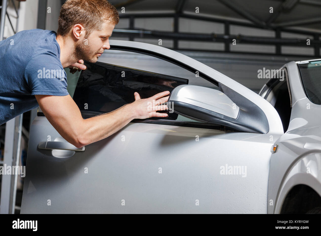 Applicazione di lamina di colorazione sul finestrino di un'automobile in un workshop Foto Stock