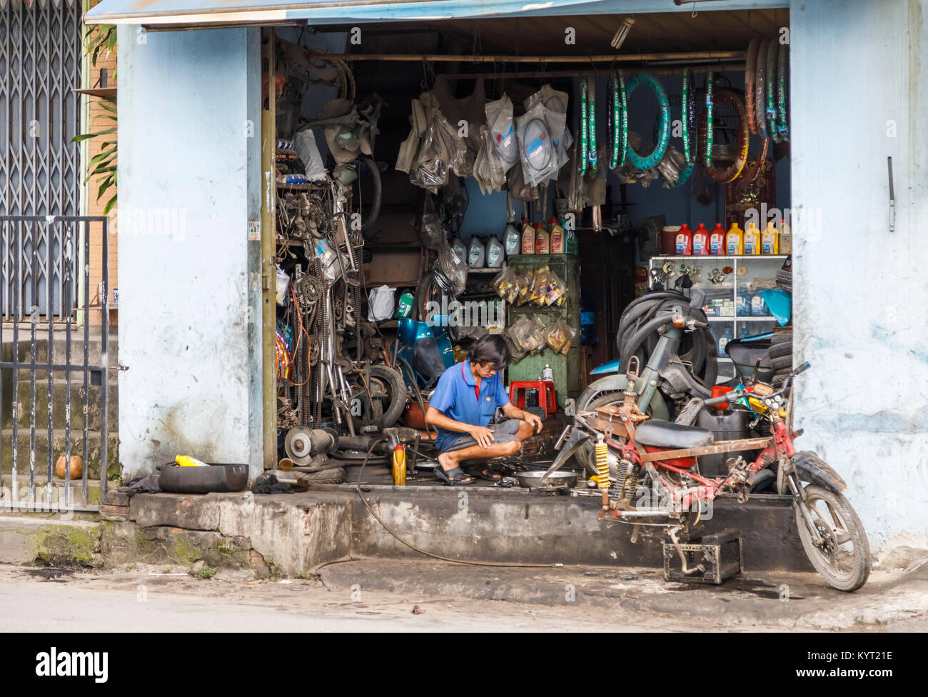 Street view nella periferia di Saigon (Ho Chi Minh City), il sud del Vietnam: vietnamita locale uomo che lavora in un open fiammante motocicletta stradale officina di riparazione Foto Stock