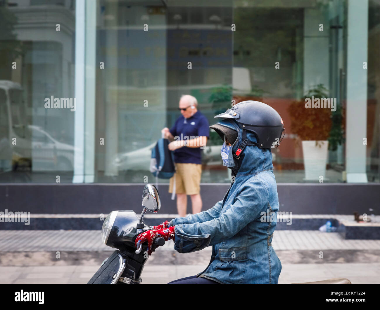 Femmina di motociclista indossando un pericoloso casco in modo errato su un cappello e un cofano: scene di strada a Saigon (Ho Chi Minh City), il sud del Vietnam Foto Stock