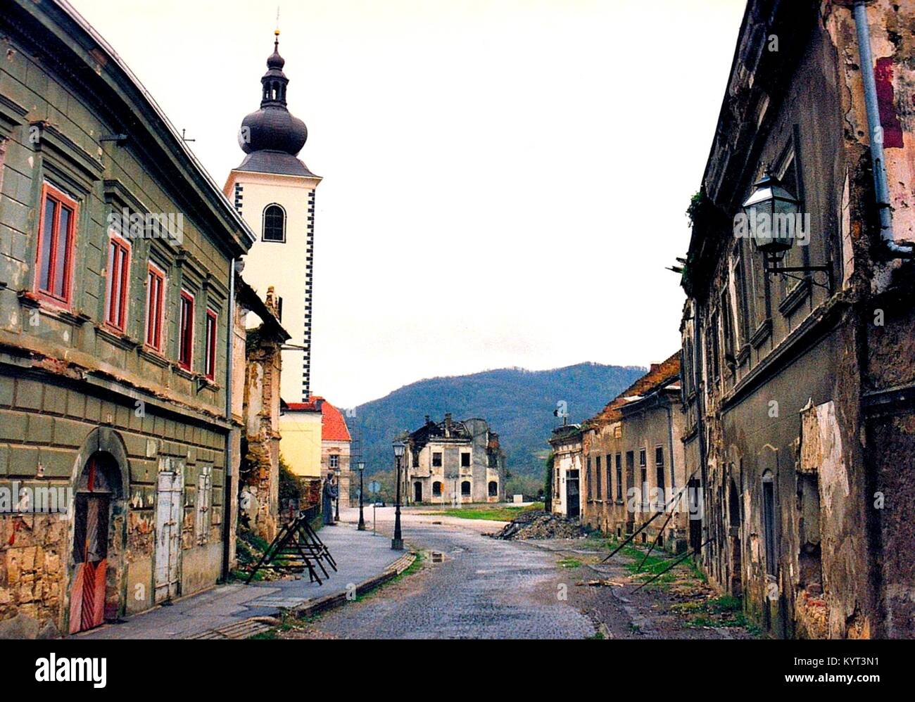 La città croata di Hrvatska Kostajnica è situato presso il fiume unà presso il confine con la Bosnia Erzegovina. Poco dopo l inizio delle guerre jugoslave la città divenne parte della Repubblica serba di Krajina fino al 1995, quando fu riconquistata da truppe croate. La parte interna della città è stata fortemente danneggiata e le chiese cattoliche sono state distrutte. Questa immagine mostra il devastato Davor Trstenjak-Street e la ricostruzione della chiesa cattolica di sette anni dopo la guerra, nel novembre 2002. Foto Stock