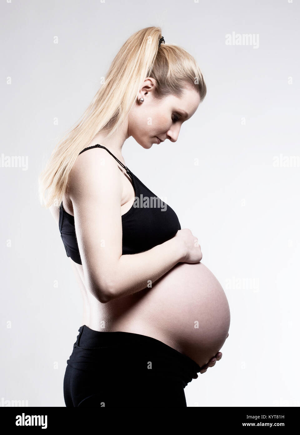 Ritratto di una gravidanza donna bionda nel reggiseno nero. Foto Stock