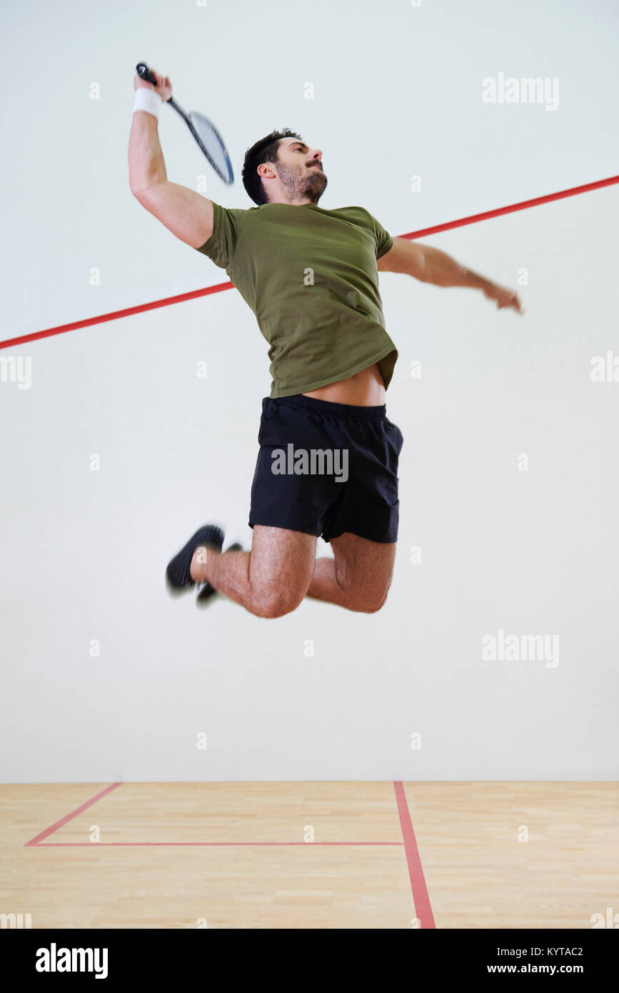 Lettore maschio jumping per colpire una palla durante la partita di squash Foto Stock
