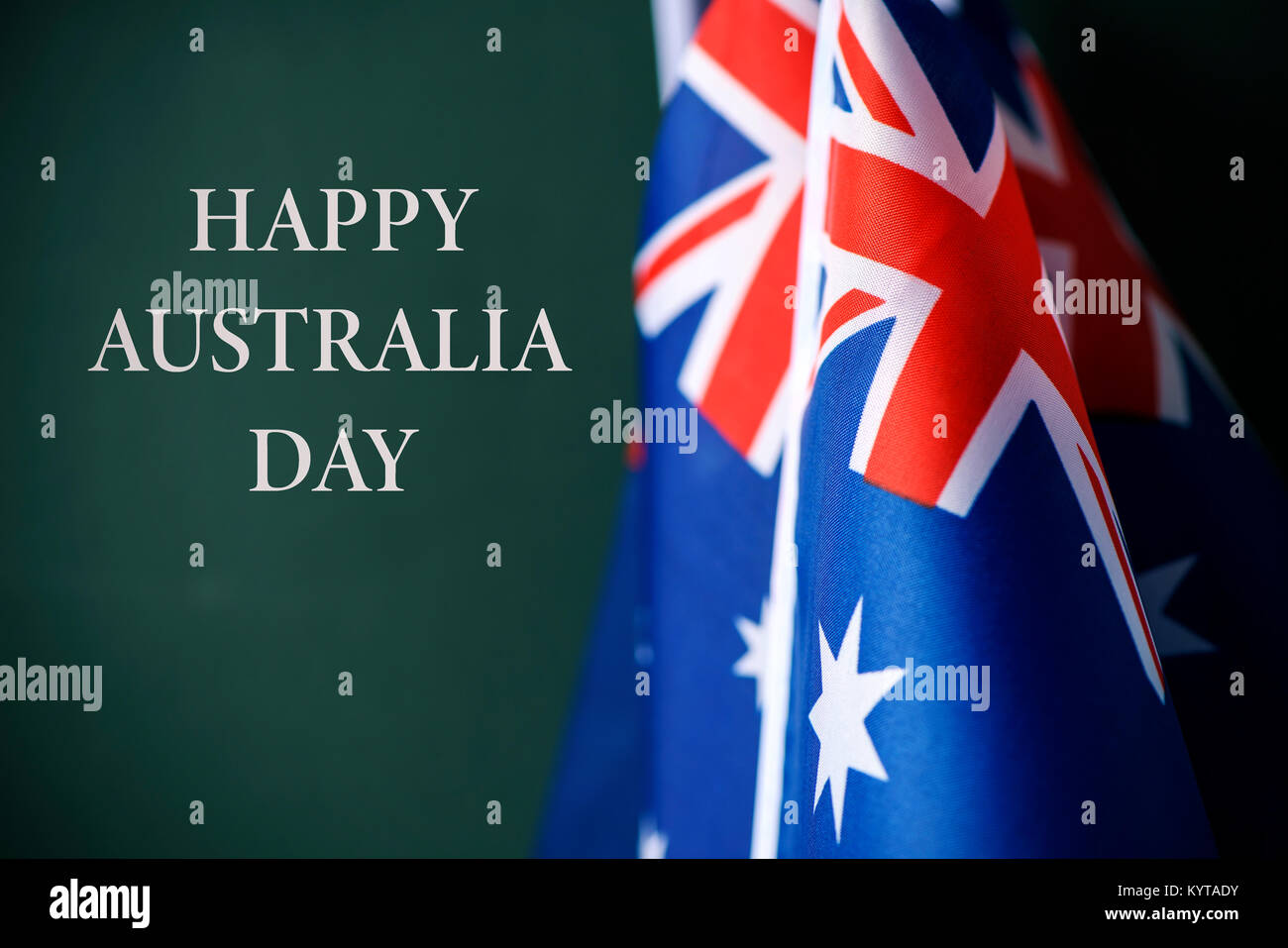 Primo piano di alcuni flag australiano e il testo happy australia giornata contro un sfondo verde scuro Foto Stock