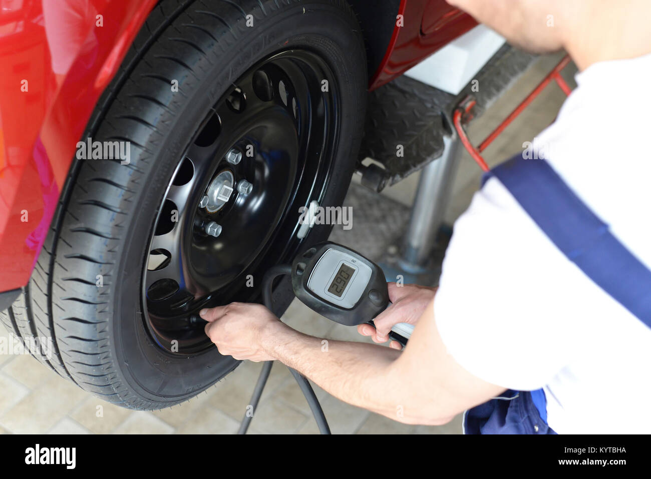 Mechanic controlla la pressione dell'aria dal pneumatico auto in un garage Foto Stock