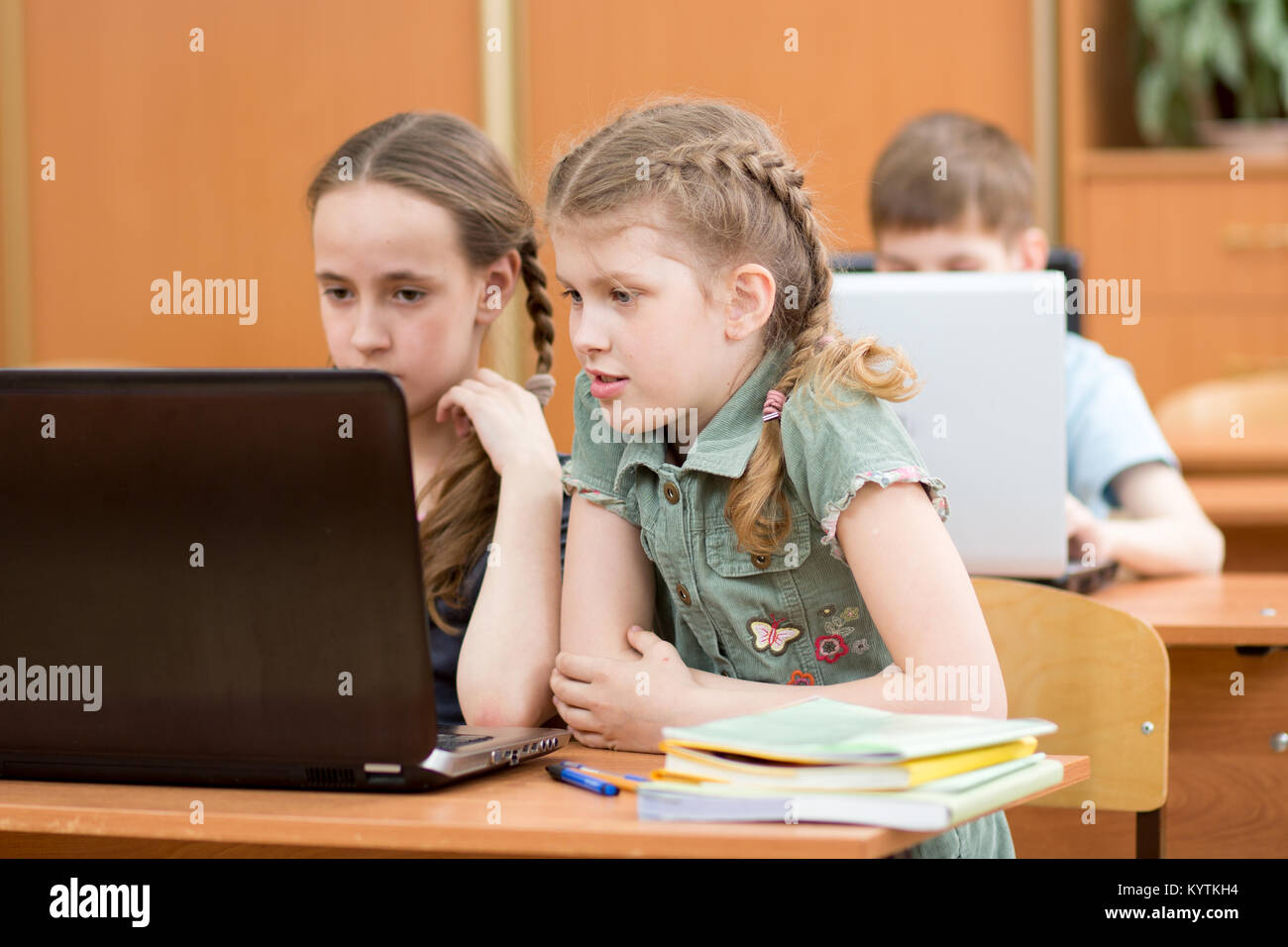 Ritratto di smart studentesse e schoolboy guardando il portatile in aula Foto Stock