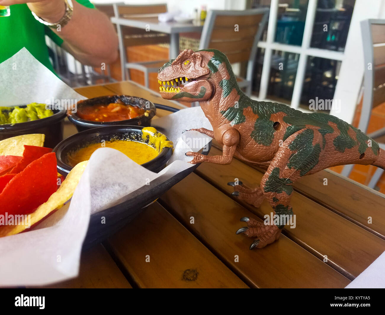Dinosauro giocattolo si affaccia su chip antipasto nel ristorante messicano Foto Stock