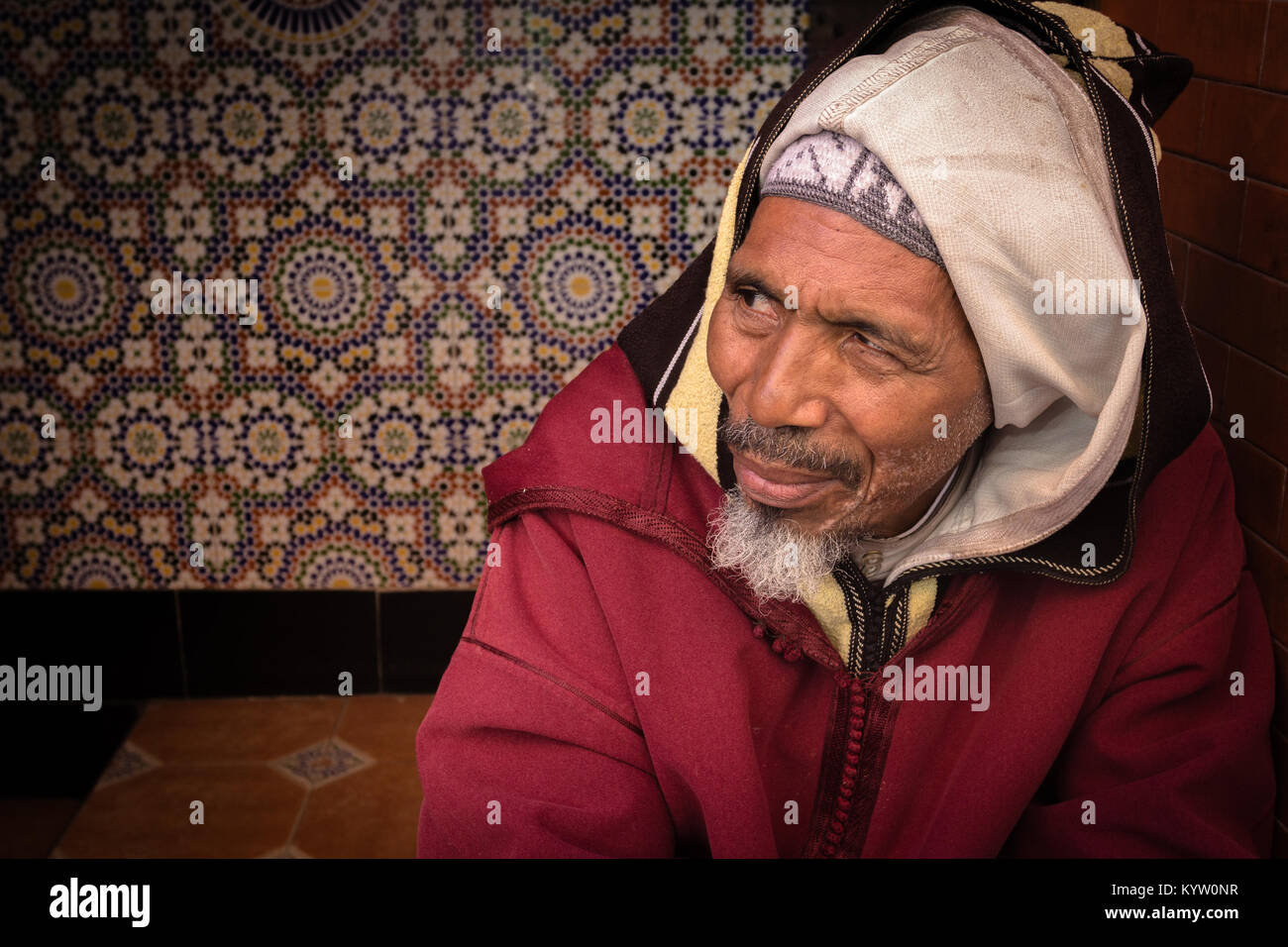 Ritratto di un gentile uomo anziano che guarda lontano dalla telecamera, seduta in una porta della Medina di Marrakesh, Marocco. Foto Stock