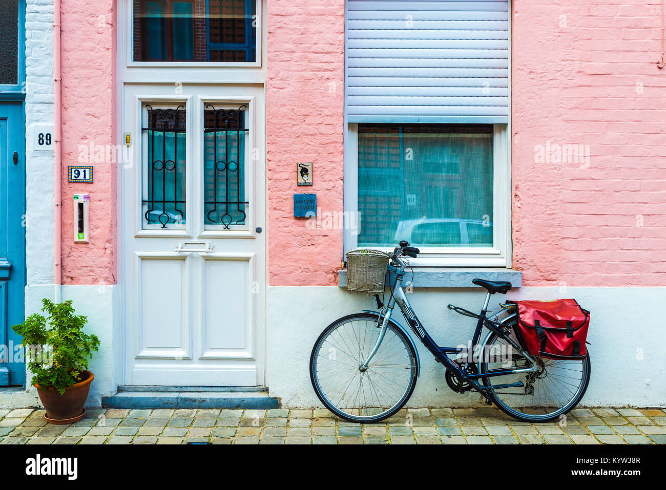 Bruges, Belgio - 31 agosto 2017: bicicletta parcheggiata di fronte a casa con parete rosa su una strada della città medievale di Bruges, Belgio Foto Stock