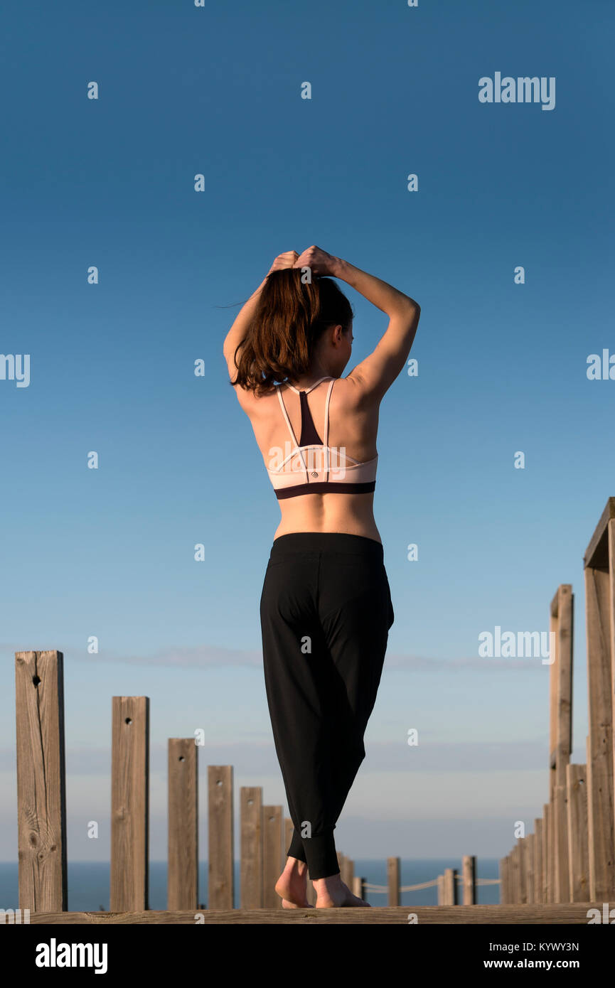 La donna la legatura i suoi capelli indietro prima di un allenamento fitness fuori dal mare. Foto Stock