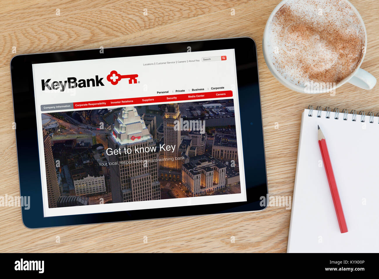 Il sito web KeyBank su un tablet iPad, su di un tavolo di legno accanto a un blocco note, matita e tazza di caffè (editoriale solo) Foto Stock