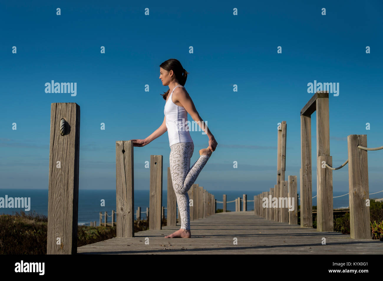 Donna in piedi facendo una gamba tratto dal mare. Foto Stock