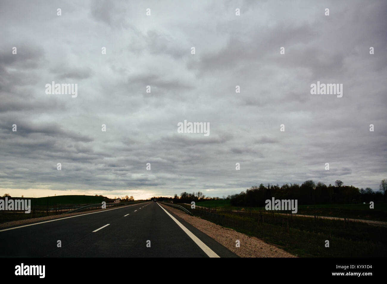 Svuotare strada asfaltata su nuvoloso giorno di estate in Lituania. Cinematic filtro applicato con grano. Foto Stock