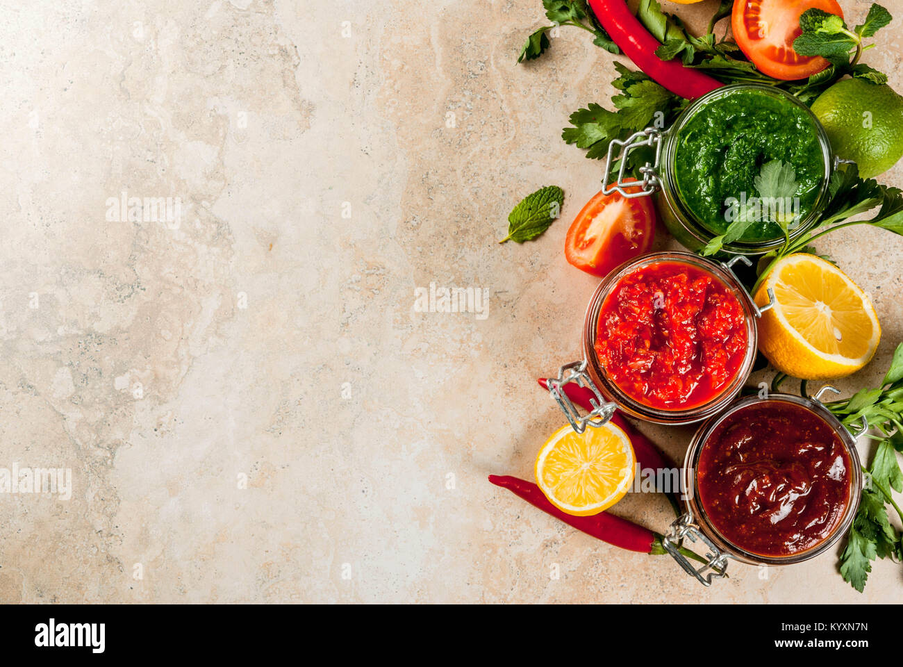 Indian cibo tradizionale, Set di tre chutney per Chaat e Sev Puri - dolce data-tamarindo, il coriandolo-verde menta e il peperoncino rosso aglio, sulla pietra beige Foto Stock