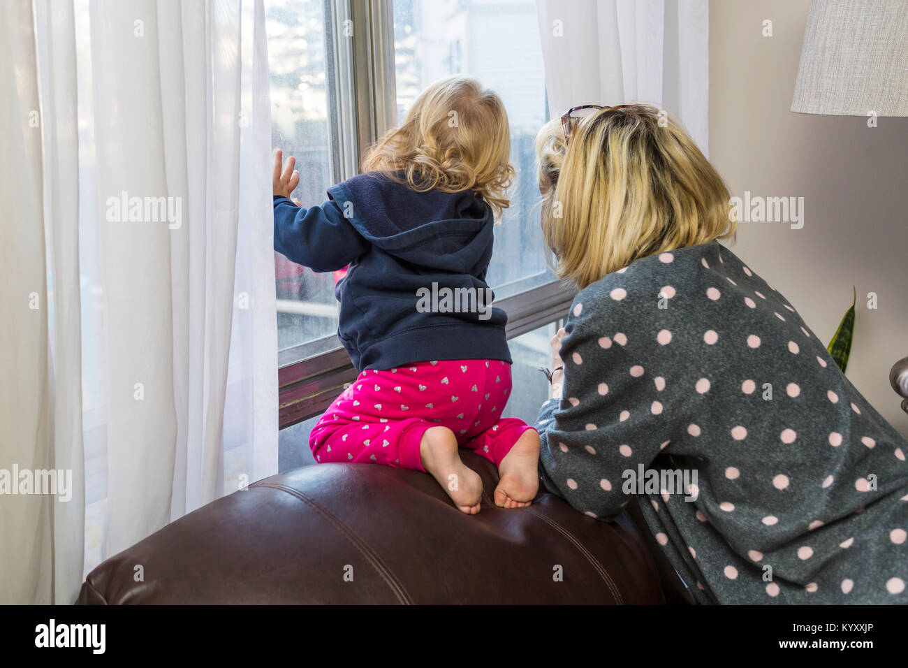 La madre e il bambino a guardare fuori dalla finestra il bambino è a rischio di caduta Foto Stock