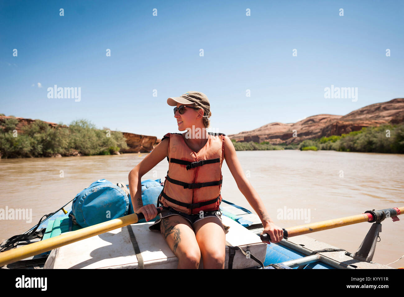 Donna che indossa il giubbotto di salvataggio mentre è seduto in zattera gonfiabile sul fiume San Juan contro il cielo chiaro durante la stagione estiva Foto Stock