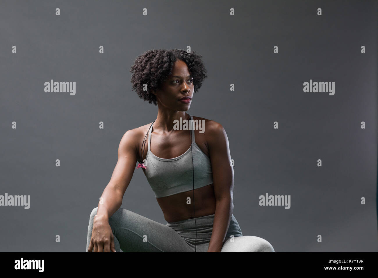 Premurosa donna che guarda lontano mentre indossa abbigliamento sportivo contro la parete in palestra Foto Stock