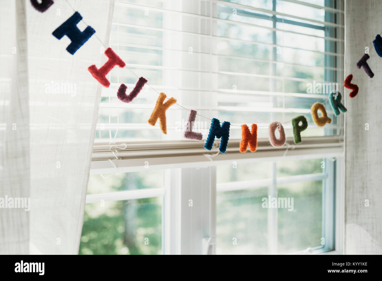 Multi alfabeto colorato decorazione appesa su una stringa da una finestra a casa Foto Stock