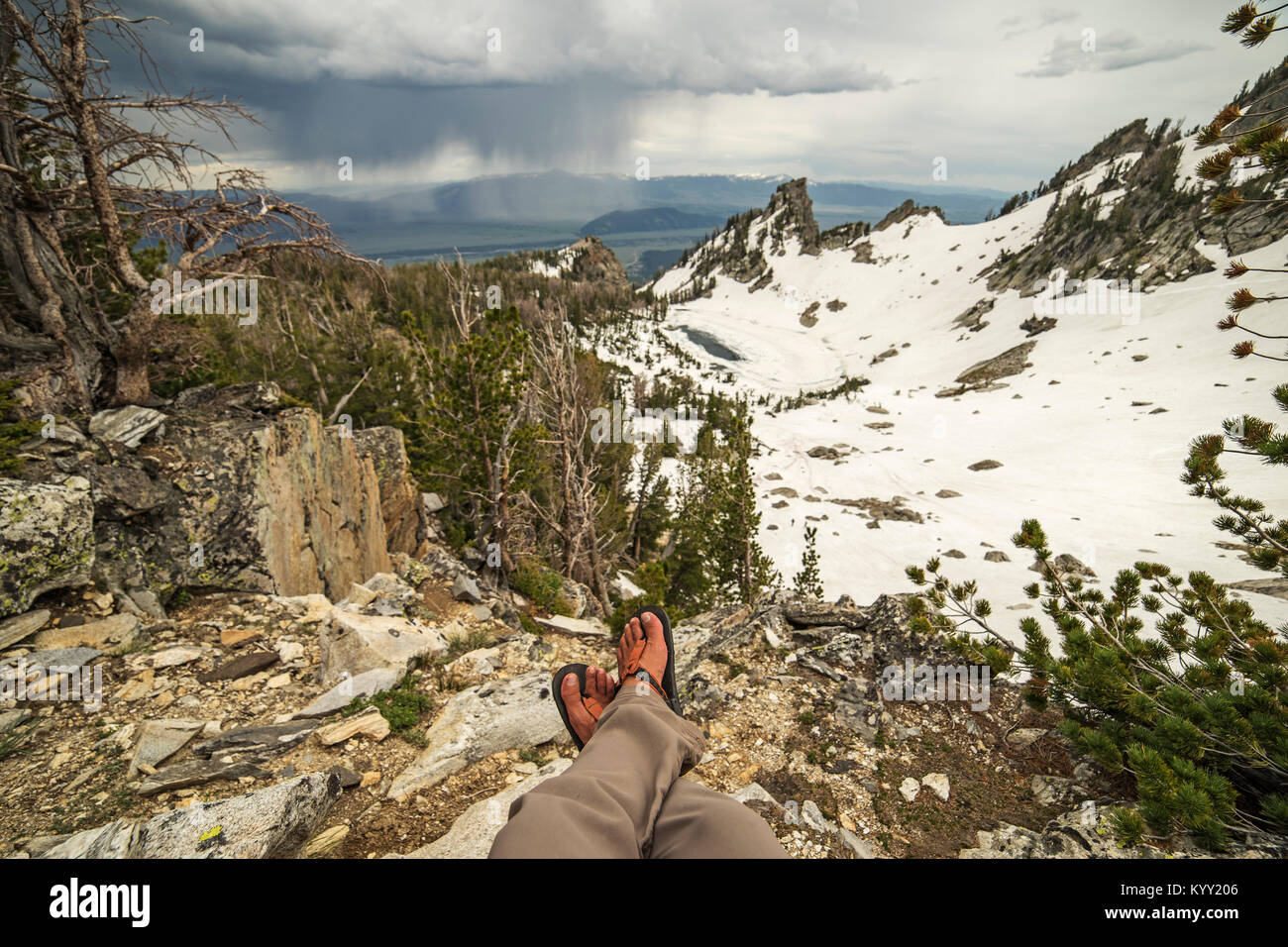 Sezione bassa di un escursionista seduti sulla montagna contro il cielo nuvoloso Foto Stock