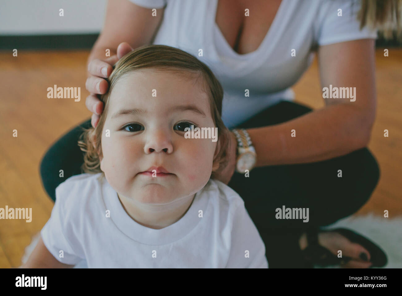 Ritratto di carino figlio con la madre sua acconciatura capelli a casa Foto Stock